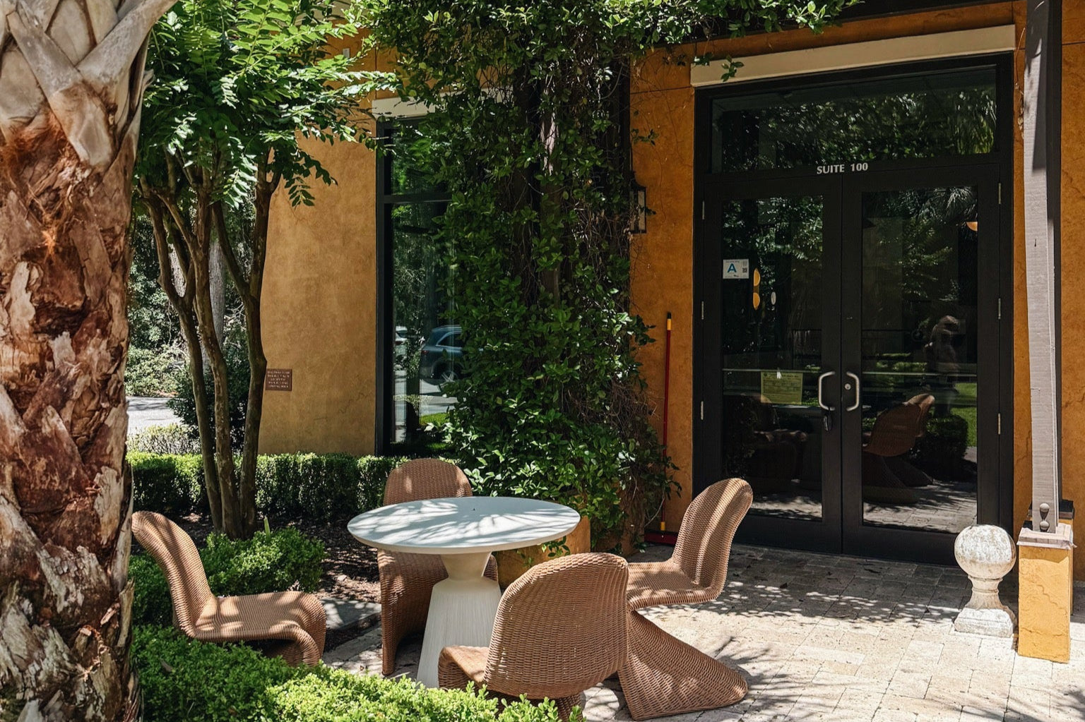 Outdoor seating area with tables and chairs in front of a building entrance. | Origin Coffee Bar | Savannah, Georgia and Hilton Head Island, South Carolina | Specialty Coffee Roaster and Cafe