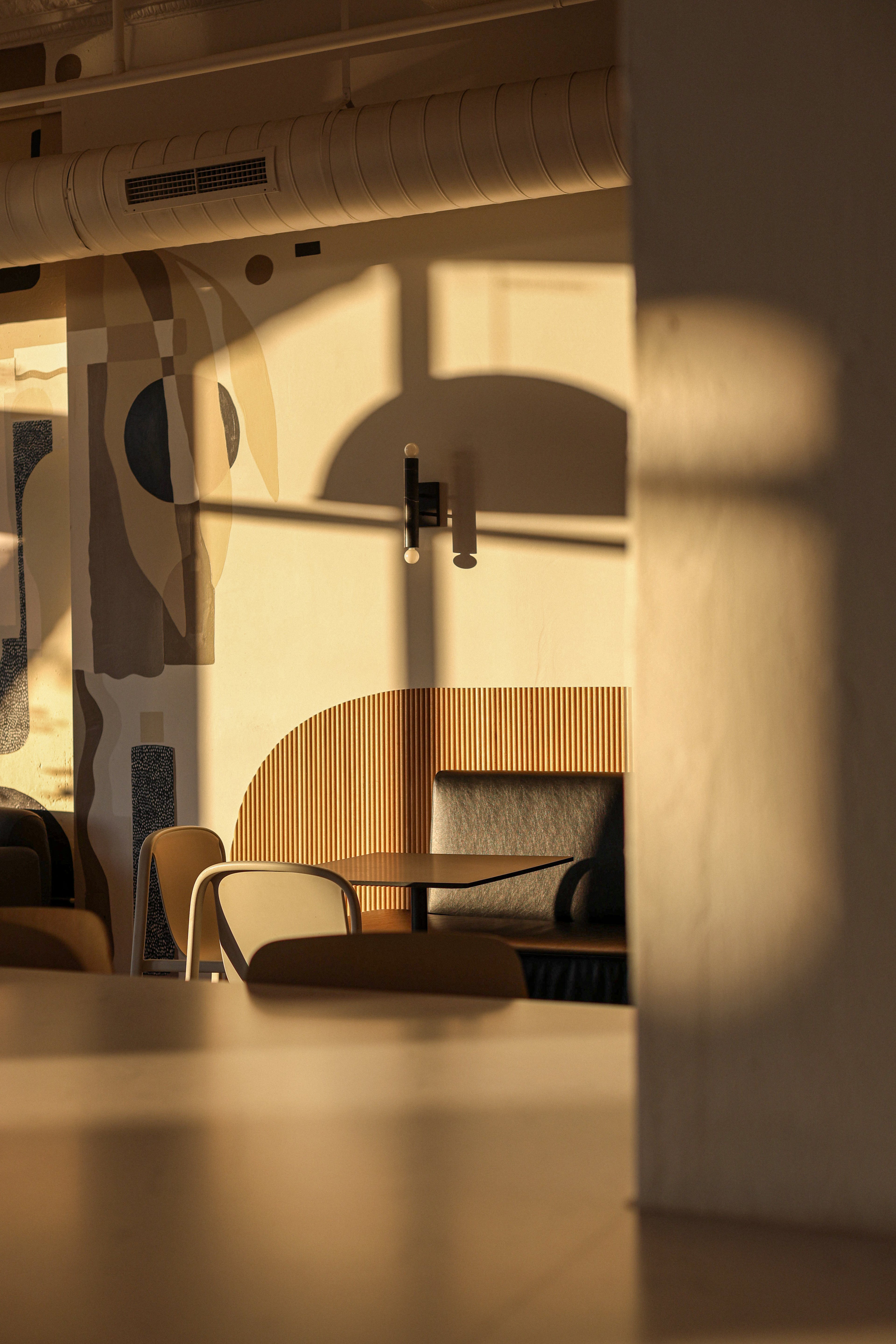 Modern cafe interior with abstract wall art and a table with chairs, bathed in warm light. Origin Coffee Bar, Savannah, GA
